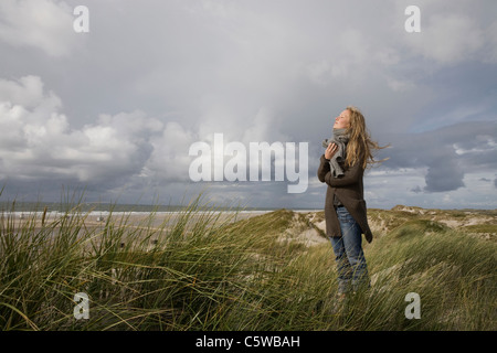 Germany, Schleswig Holstein, Amrum, Young woman on grassy sand dune