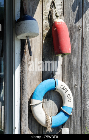 Classic Cape Cod scene with lobster buoys and life ring on weathered wood of exterior of building, USA Stock Photo