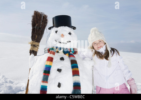 Germany, Bavaria, Munich, Girl (8-9) standing next to snowman, portrait Stock Photo