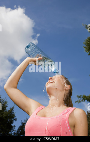 Germany, Berlin, Young woman pouring water over face, portrait