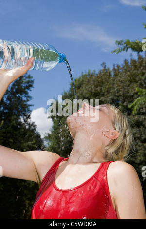Germany, Berlin, Woman pouring water over face, portrait