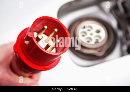 Hand of woman holding high voltage cable near electric car, close up Stock Photo