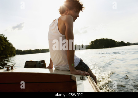 Germany, Berlin, Young man sitting on motor boat Stock Photo