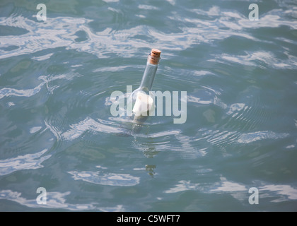 Germany, Message in bottle floating in sea Stock Photo