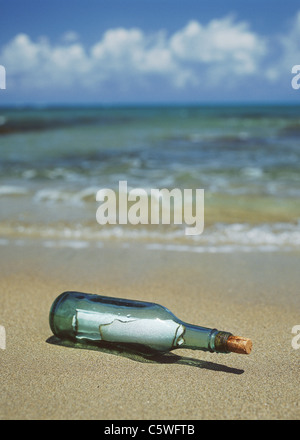 Germany, Bottle with message in sand at beach Stock Photo