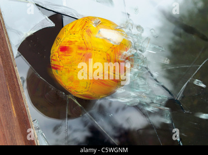 Close up of broken glass window by soccer ball Stock Photo