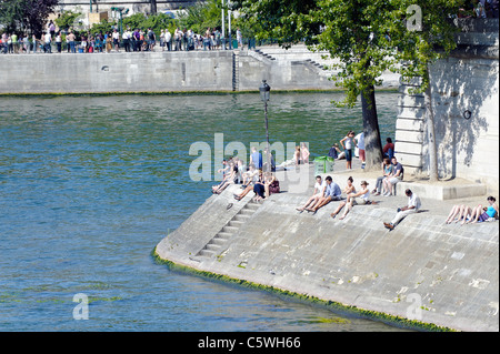 Parisians sunbathing on the banks of the River Seine Stock Photo