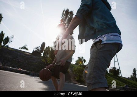 Germany, Berlin, Teenage boys playing basketball in playground Stock Photo