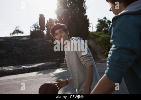 Germany, Berlin, Teenage boys playing basketball in playground Stock Photo