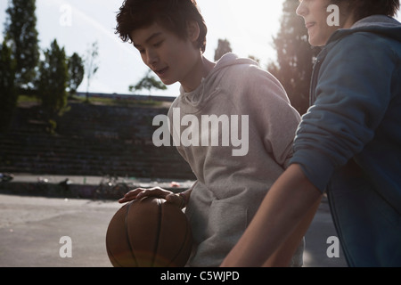 Germany, Berlin, Teenage boys playing basketball in playground Stock Photo