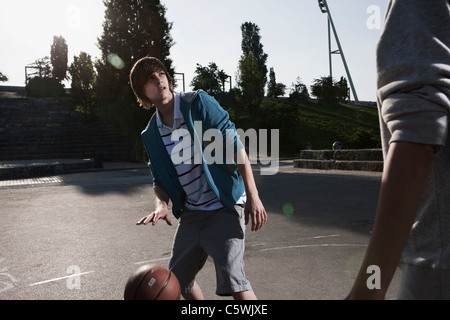 Germany, Berlin, Teenage boys playing basketball in playground Stock Photo