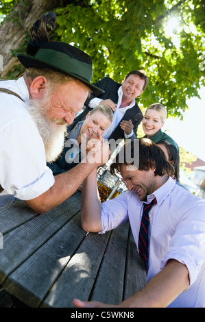 Germany, Bavaria, Upper Bavaria, Two men in beer garden arm wrestling Stock Photo
