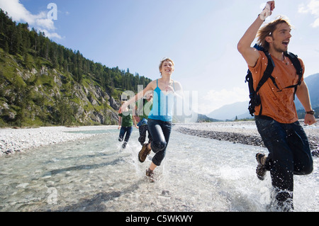 Germany, Bavaria, TÃ¶lzer Land, Young friends running through river Stock Photo