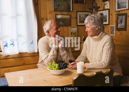 Senior couple sitting at table, smiling Stock Photo