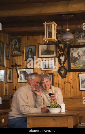Senior couple sitting at table in Log Cabin Stock Photo