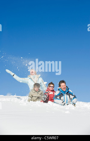 Italy, South Tyrol, Seiseralm, Family sitting in snow, laughing Stock Photo