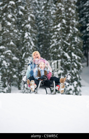 Italy, South Tyrol, Seiseralm, Mother and daughter (6-7) sledding downhill, laughing, portrait Stock Photo