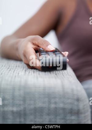 closeup of woman on sofa, changing tv channel with remote control. Front view, copy space Stock Photo