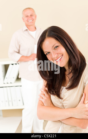 Casual businesswoman attractive smiling crossed arms businessman in background Stock Photo