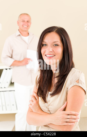 Casual businesswoman attractive smiling crossed arms businessman in background Stock Photo