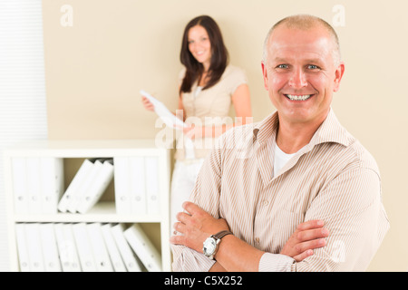 Casual businessman attractive smiling crossed arms businesswoman in background Stock Photo