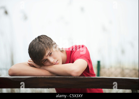 Germany, Bavaria, Young man resting head on arms, portrait Stock Photo