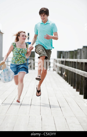 Germany, Bavaria, Ammersee, Young couple running on pier Stock Photo