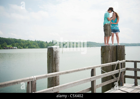 Germany, Bavaria, Ammersee, Young couple standing on wooden post Stock Photo