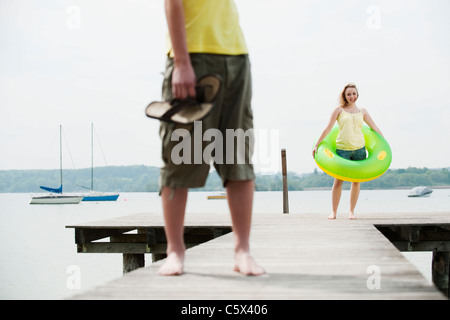 Germany, Bavaria, Ammersee, Couple on jetty, woman holding floating tire Stock Photo