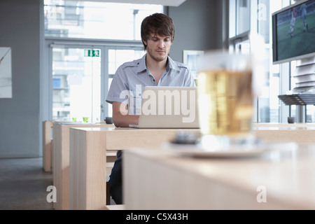 Germany, Cologne, Young man in cafe using laptop Stock Photo