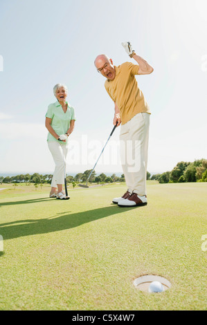Spain, Mallorca,  Senior couple on golf course, man cheering Stock Photo