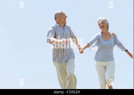 Senior couple running hand in hand, portrait