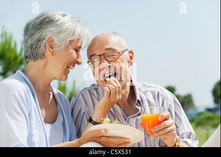Spain, Mallorca, Senior woman feeding grapes to senior man, laughing, portrait Stock Photo