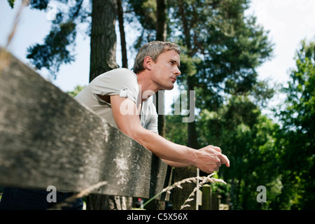 Germany, Hamburg, Man leaning against wooden fence Stock Photo