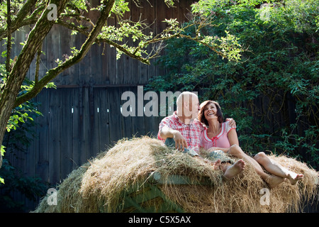 Germany, Bavaria, Couple sitting on haystack, smiling, portrait Stock Photo