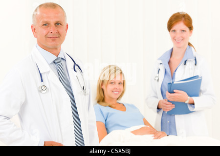 Two medical doctors professional with hospital patient lying in bed Stock Photo