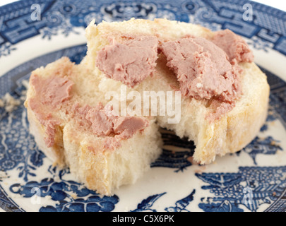 Liver pate spread onto a slice of halved broken white bread Stock Photo