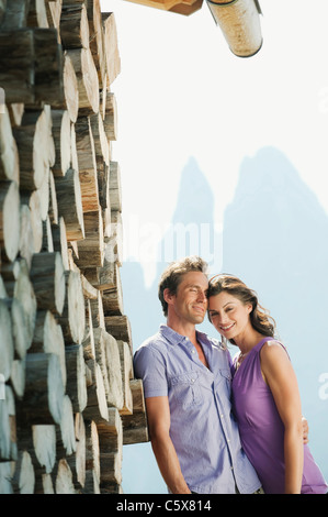 Italy, South Tyrol, Seiseralm, Couple leaning against pile of wood pile, portrait Stock Photo