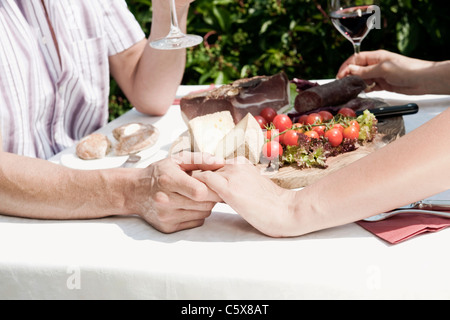 Italy, South Tyrol, Couple having cold snack, holding hands, mid section Stock Photo