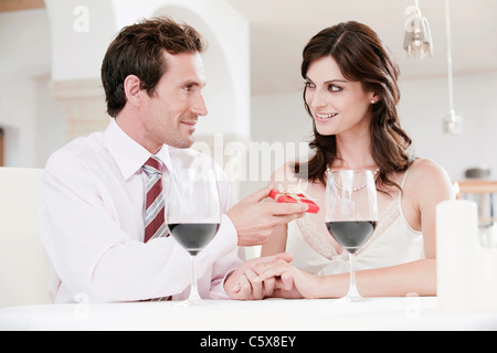Couple sitting at table in restaurant, man holding gift parcel Stock Photo