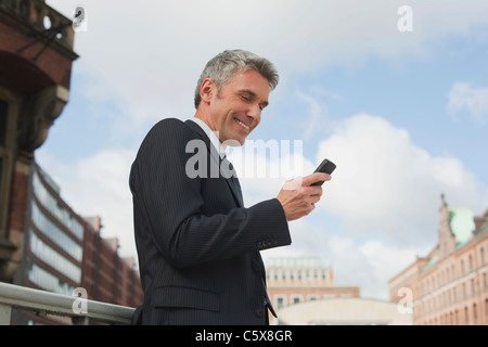 Germany, Hamburg, Businessman using mobile phone, smiling, portrait Stock Photo