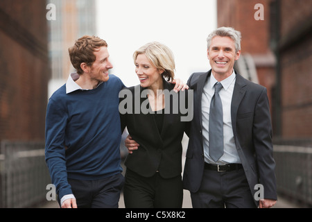 Germany, Hamburg, Three Business people walking side by side, smiling, portrait Stock Photo