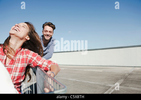 Germany, Berlin, Young man pushing young woman in shopping cart Stock Photo