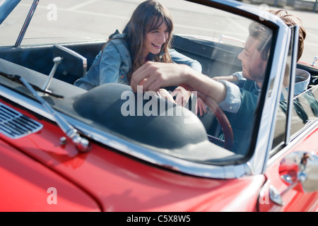 Germany, Berlin, Young couple sitting in cabriolet, laughing, portrait Stock Photo
