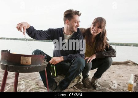 Germany, Berlin, Lake Wannsee, Young couple having a barbecue Stock Photo