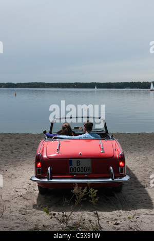 Germany, Berlin, Lake Wannsee, Young couple in cabriolet looking at lake, rear view Stock Photo