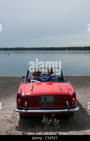 Germany, Berlin, Lake Wannsee, Young couple in cabriolet embracing, side view, portrait Stock Photo