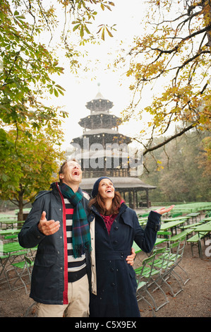Germany, Bavaria, Munich, English Garden, Couple in rainy beer garden, Chinese tower in background, portrait Stock Photo