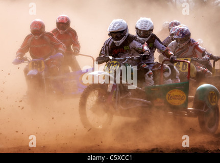 Riders racing through the dust at the start of a sidecar motocross race Stock Photo