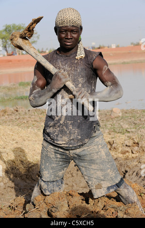 Africa MALI Mopti , clay architecture - worker mixing clay and straw for making of clay brick for building Stock Photo